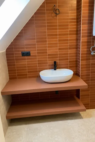 Hotová koupelna, oranžový obklad za umyvadlem na dvou deskách